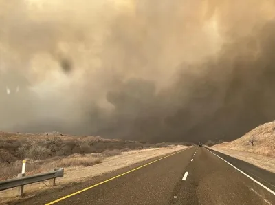 Two-lane asphalt road with smoke filling the sky in Texas Panhandle.