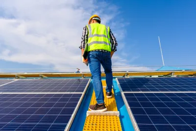 Worker standing between solar panels on roof