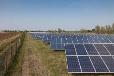 Solar panels are lined up on agricultural land.