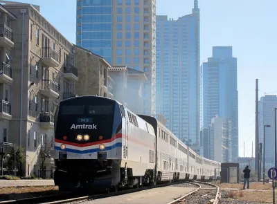 Texas Eagle Amtrak train pulling into station in Austin, Texas with glass high-rise buildings in background.