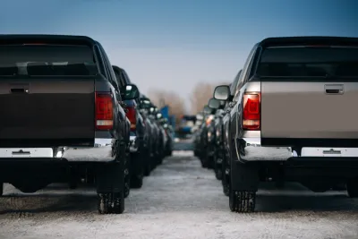 Large pickup trucks are parked in neat rows extending into the fuzzy background of the image.