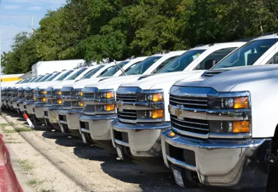 A row of white pickup trucks at a car dealership.