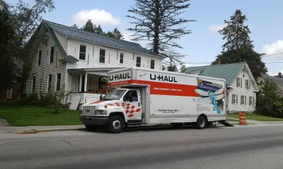 U-Haul moving truck in front of white house and trees