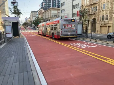 Red bus only lanes on Van Ness Avenue in San Francisco, California with bus stopped at station.