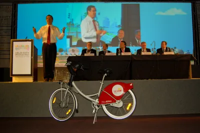Gil Penalosa speaking on a stage at Velo-city conference in Seville, Spain, with bicycle in foreground