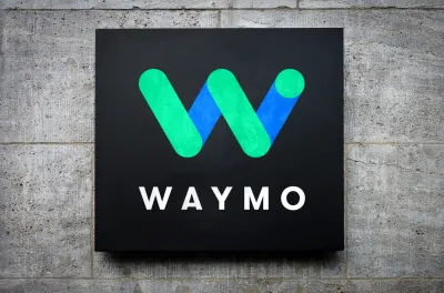Blue and green Waymo logo on black square mounted on grey concrete background