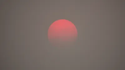 A red sun appears on the horizon, as obscured by haze from wildfire smoke.