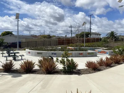 Concrete walkway with landscaping, decorative tiles, and picnic tables in a Los Angeles County park.