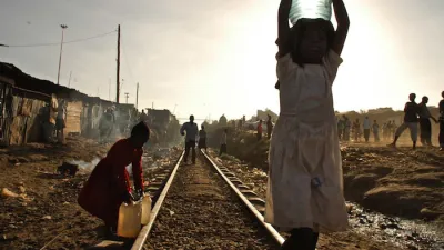 Two young girls carry water on the train tracks that run through the Kibera Slum