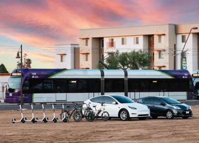 Rendering of electric scooters, electric cars, light rail train, and apartments in background.