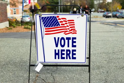 "Vote Here" sidewalk sign with American flag