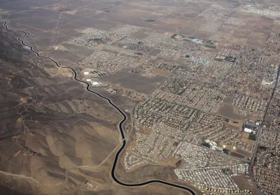 Aerial view of California Squeduct snaking past housing developments in the Mojave Desert