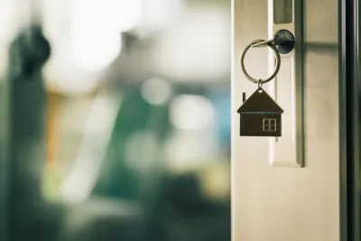 Close-up of key in door lock with house-shaped keychain hanging from it