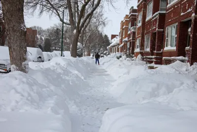 Snow-covered Chicago sidewalk with piles of snow on either side and red brick homes on the right