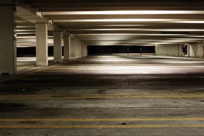 Empty parking garage at night with yellow lines marking spots and fluorescent lighting
