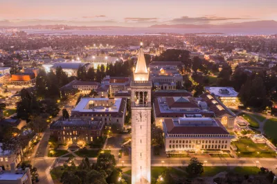 Aerial view at dusk of UC Berkeley campus with tall tower in foreground and San Francisco Bay in the background