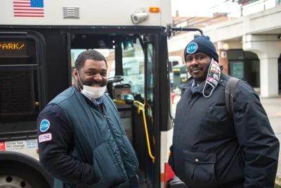 Two Chicago transit operators standing in front of a bus and smiling at the camera