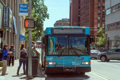 Bus stop in Pittsburgh, Pennsylvania with blue bus and passengers boarding