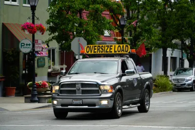 Pick-up truck on small town street with yellow "Oversize Load" sign