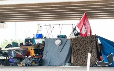 Encampment of unhoused people with tents and draped fabrics in Austin, Texas