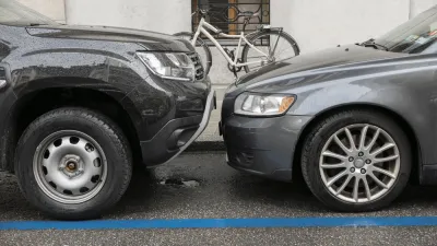Two grey cars parked head to head at a curb with a white bike in background