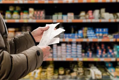 Close-up of person holding receipt with grocery store shelves in background