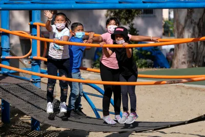Children wearing COVID-19 masks on playground equipment