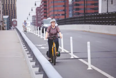 Woman on bicycle in protected bike lane on Boston bridge