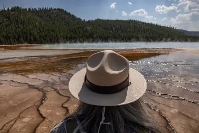 View of park ranger with tan hat from behind, ranger looking out at Grand Prismatic Spring in Yellowstone National Park, Wyoming
