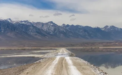 Unpaved road through Owens Lake bed with Sierra Nevada mountains in the background