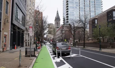 Green parking-protected bike lane in Philadelphia with old church in background