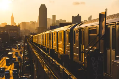 Golden sunset view of New York City subway train on elevated track with Empire State Building in background