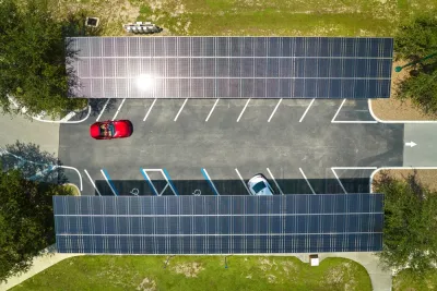Overhead view of parking lot with solar panel canopies over parking spots and red car driving in