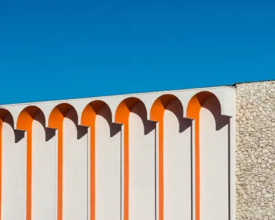Close-up of white building with orange arch details against blue sky in Palm Springs, California
