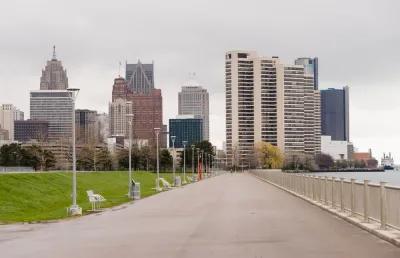 Waterfront walkway with benches and Detroit skyline in the background