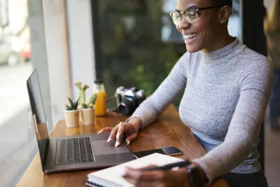Woman sitting at countertop with laptop facing window