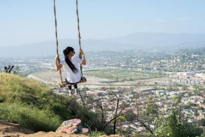 Girl swinging on rope swing overlooking Los Angeles