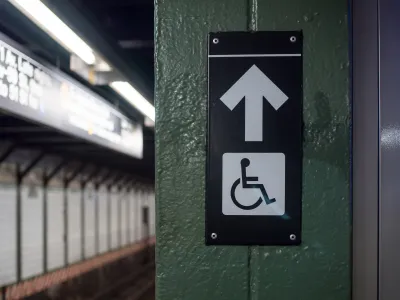 Accessible elevator sign with arrow on a New York City subway platform
