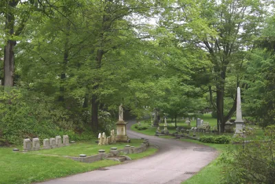 Gravestones along pathway in green Mount Auburn Cemetery