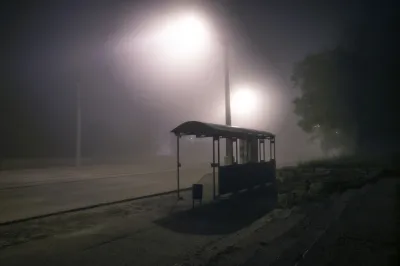 Bus shelter from behind at night with mist and streetlights