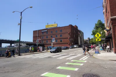 Pedestrians in zebra crosswalk with green bike lane in downtown Seattle, Washington with three-story brick building in background