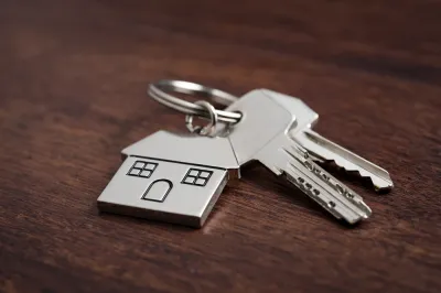 House key with house-shaped keychain on table