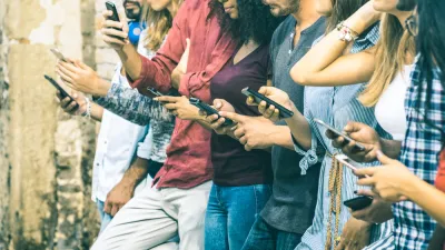 A row of young people outdoors using smartphones