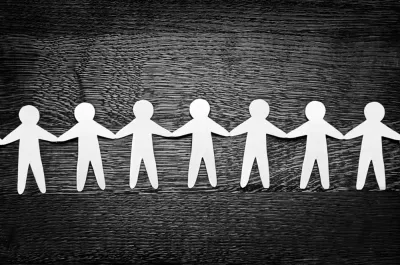 Cutout paper people on wooden table and artistic shadows