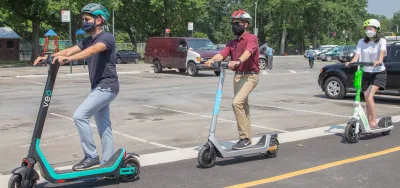 Three people wearing helmets riding electric scooters in New York City