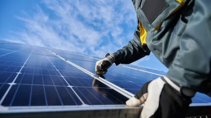 Close-up of technician wearing gloves installing photovoltaic solar panel.