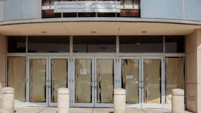 Vacant retail storefront with multiple glass doors lined with brown paper and a removed neon sign.