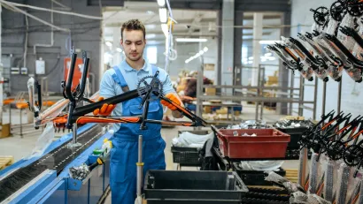 Worker in bicycle factory holding black and orange bike frame.