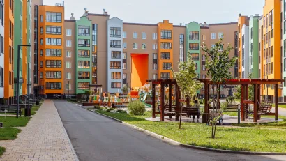 Colorful seven-story apartment buildings around a grasy courtyard with wooden gazebos.