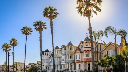 Historic Victorian homes in Huntington Beach, California with tall palm trees on a sunny day.
